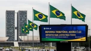 Cena urbana brasileira com edifício governamental, bandeiras e painel de impostos, ilustrando reforma tributária entenda quais